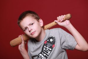 a boy uses two hands to hold a baseball bat across his shoulders, behind his head