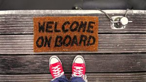 feet in front of a mat that reads "welcome on board"