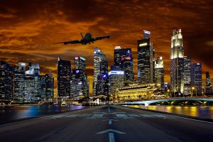 in the foreground, an airplane approaches a runway against a nighttime cityscape background