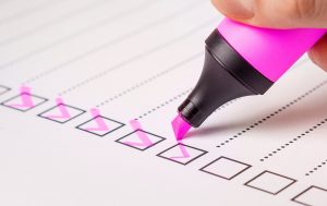 someone checking items off a checklist with a pink highlighter