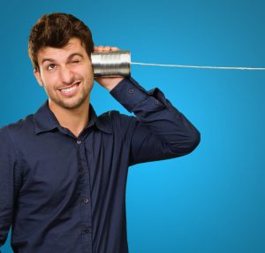 Young Man Listening From Tin Can Phone On Blue Background