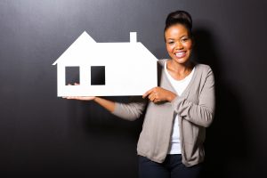 happy african american woman showing house symbol over black background