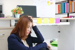 Tired overworked young Asian business woman suffering from severe depression in office.