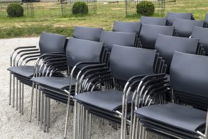 a large cluster of black plastic, metal-framed conference chairs in stacks of five